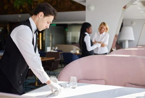 [freepicdownloader.com]-young-caucasian-man-setting-table-while-two-female-coworkers-discussing-work-normal